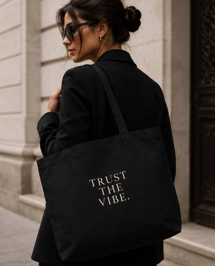A black canvas tote bag with white text reading 'TRUST THE VIBE.' shown in a lifestyle collage.